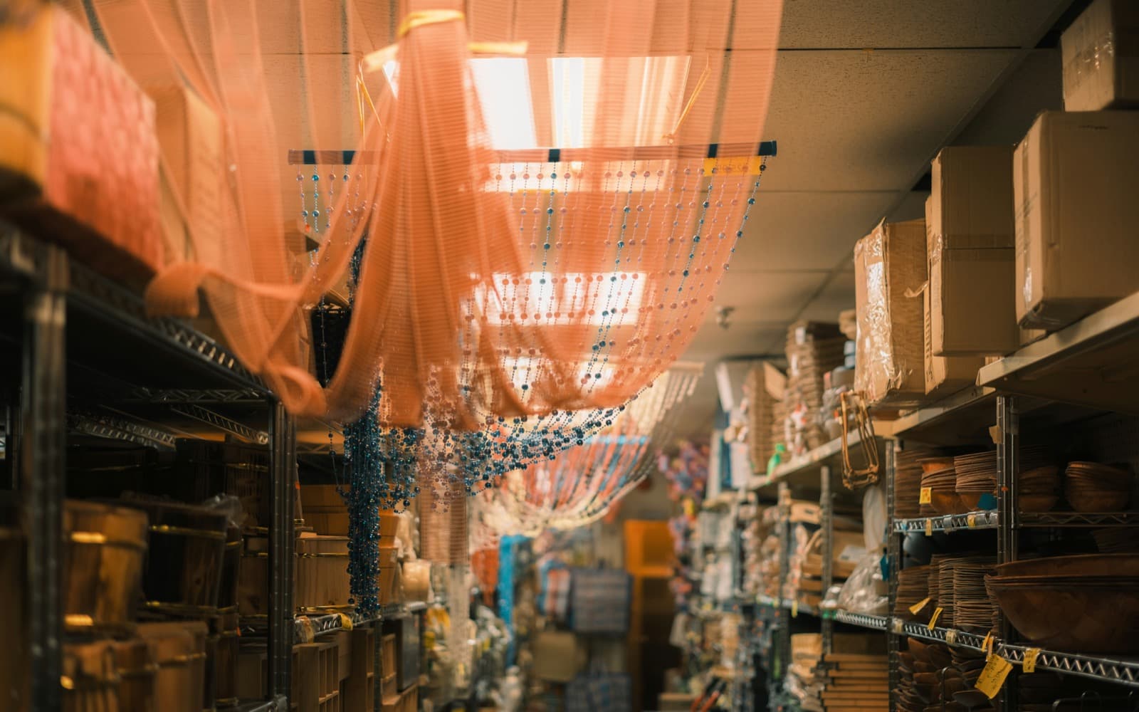 Pasillo de una tienda con estantes de metal, cajas de cartón y cestas de madera
