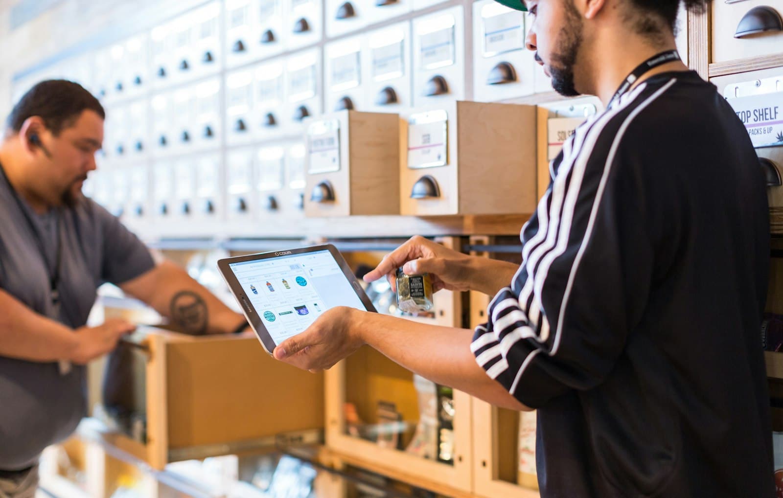 Dos personas revisan el inventario de una tienda con una tableta junto a un mueble de cajones